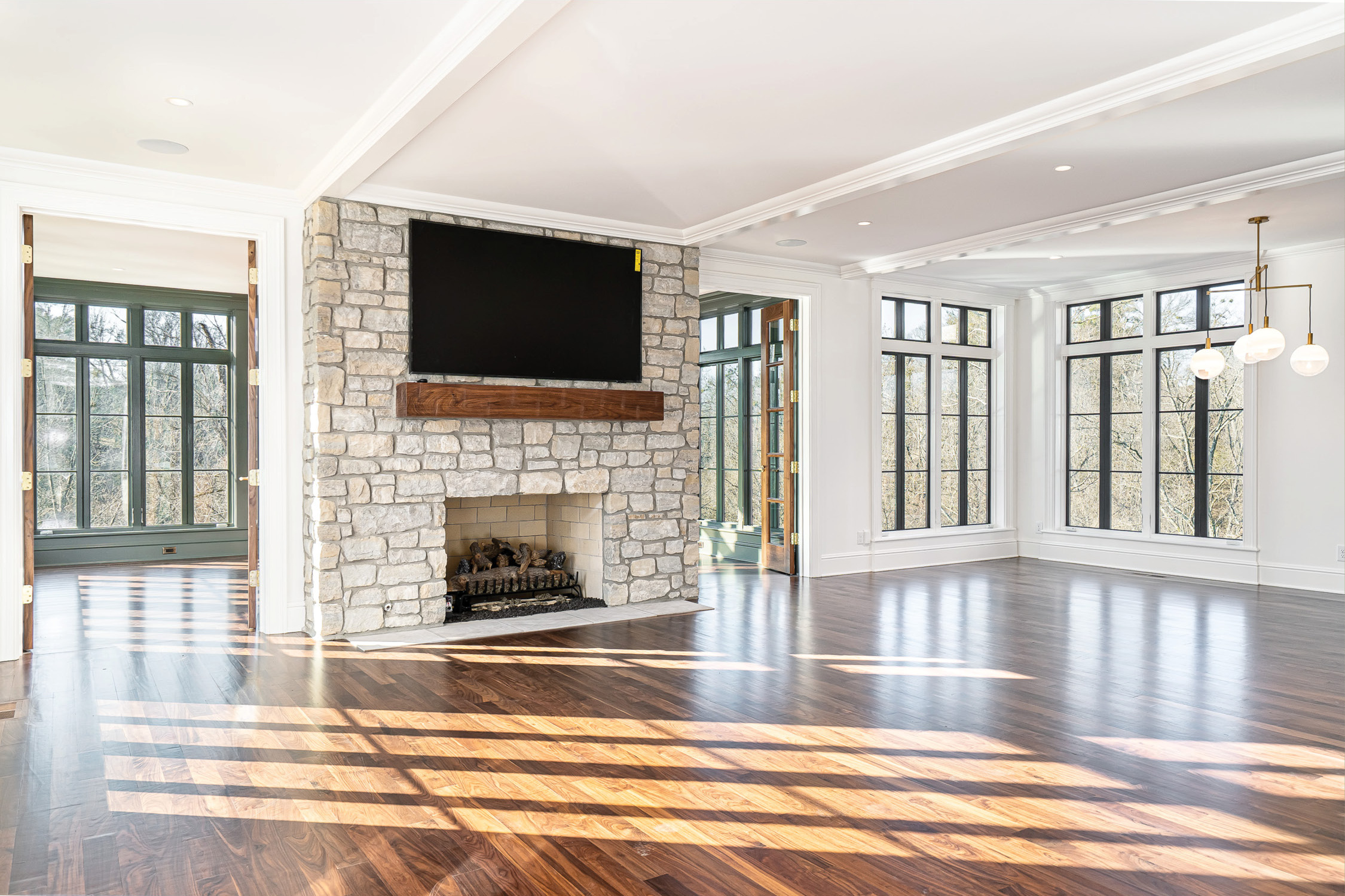 Great room with a stone fireplace, walnut floors and a wall of casement windows