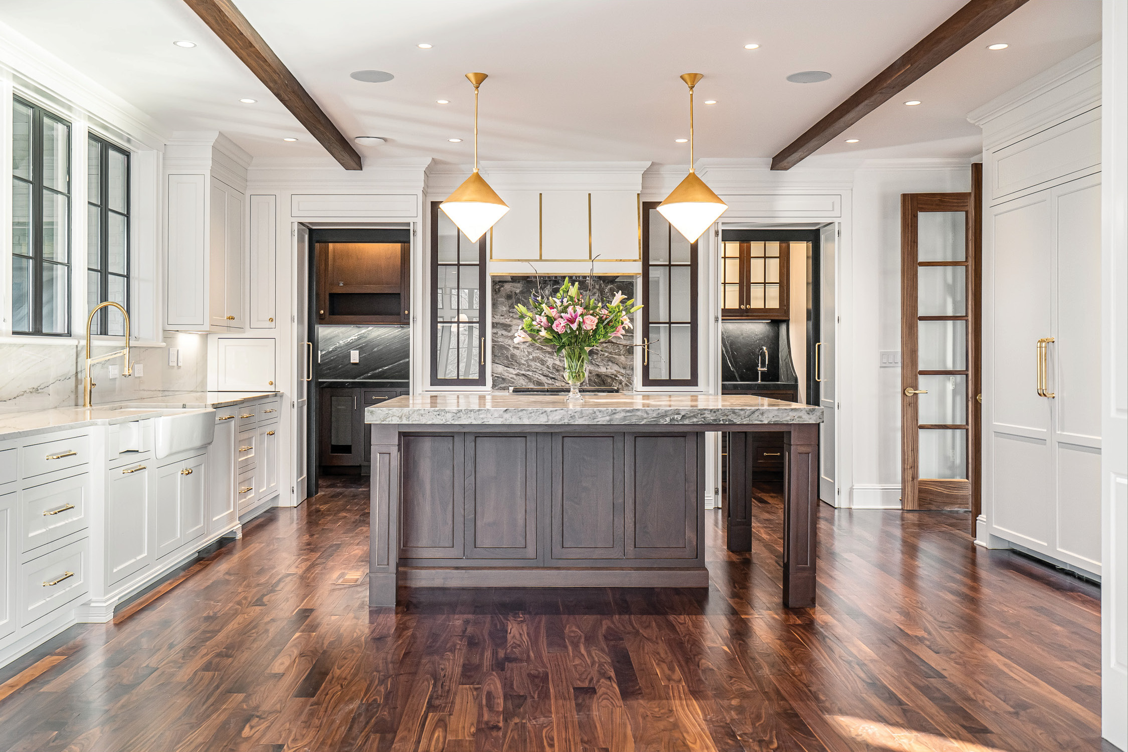 Chef’s kitchen with a marble backsplash, brass fixtures and Sub-Zero and Wolf appliances