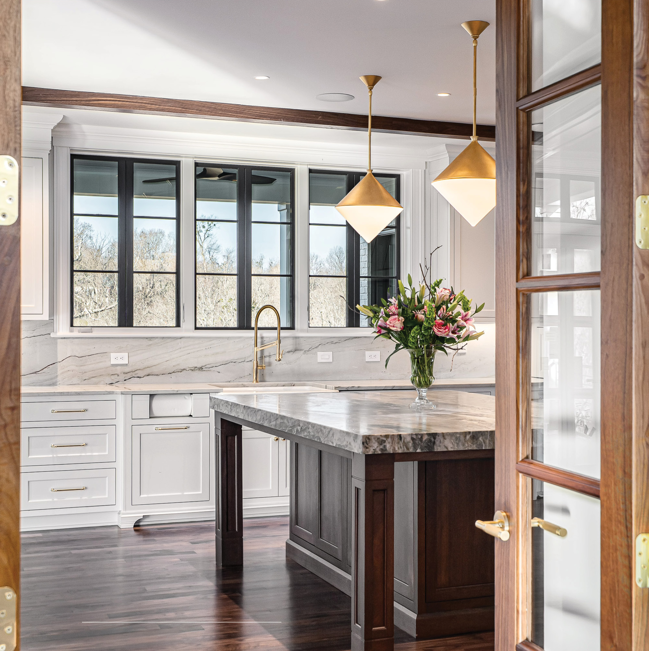 Kitchen island in figured marble, seen through walnut and glass doors