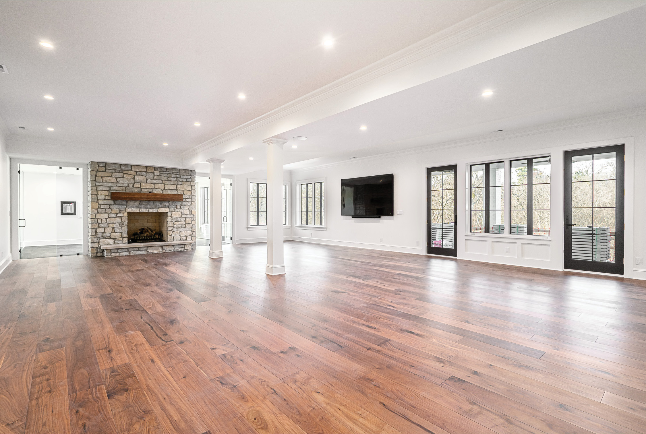 Lower level with a stone fireplace, columns and walnut floors